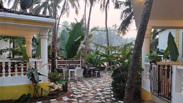 A paved courtyard with a tiled pathway, outdoor seating, and lush greenery.