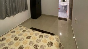A bedroom with a bed, a wardrobe, and a bathroom visible through an open door.