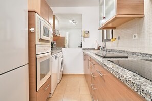 A modern kitchen with built-in appliances, a washing machine, and a granite countertop. - Villa 'El Nido' with Sea View, Wi-Fi and Air Conditioning (Almuñécar)