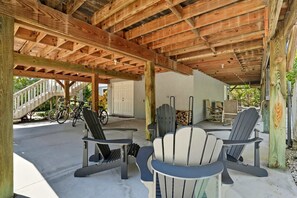 Un espacio de estar techado al aire libre con sillas Adirondack y una bicicleta.