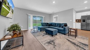 A modern living room with a sectional sofa, a coffee table, and a rug.
