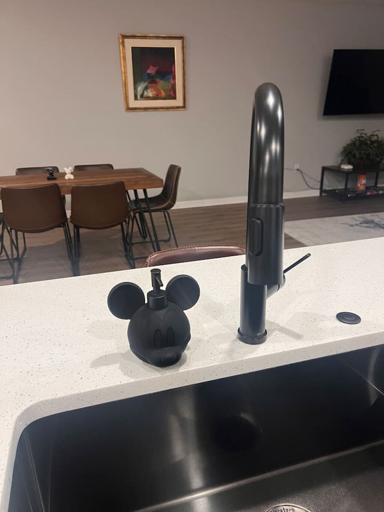 Une cuisine dotée d’un robinet moderne, d’un distributeur de savon à l’effigie de Mickey Mouse et d’un coin repas avec des chaises et une table.