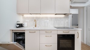 A modern kitchen with white cabinets, a built-in oven, and a dishwasher. - Spacious Apartment in the Center | Balcony and Air Conditioning (Wrocław)