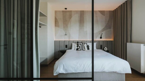 Ein modernes Schlafzimmer mit einem Bett, Nachttischen und einer Wandleuchte.