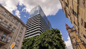 A modern high-rise building with a glass facade, surrounded by older buildings with traditional architecture. - Stylish Studio in the Center of Katowice | Balcony | Parking (Katowice)