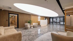 A modern reception area with a large, illuminated ceiling feature, a reception desk, and seating arrangements. - Stylish Studio in the Center of Katowice | Balcony | Parking (Katowice)