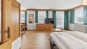 A hotel room with a bed, a desk, a television, and a window with curtains. - Apartment in Mittersill With Mountain View (Mittersill)