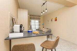 Eine kleine Küche mit Kaffeemaschine, einem Esstisch und zwei Stühlen.