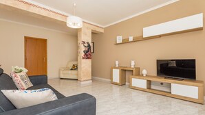 Un salon avec un canapé, un meuble pour la télévision et une porte.