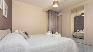 Une chambre d’hôtel avec un grand lit, une table de chevet, un miroir et une armoire.