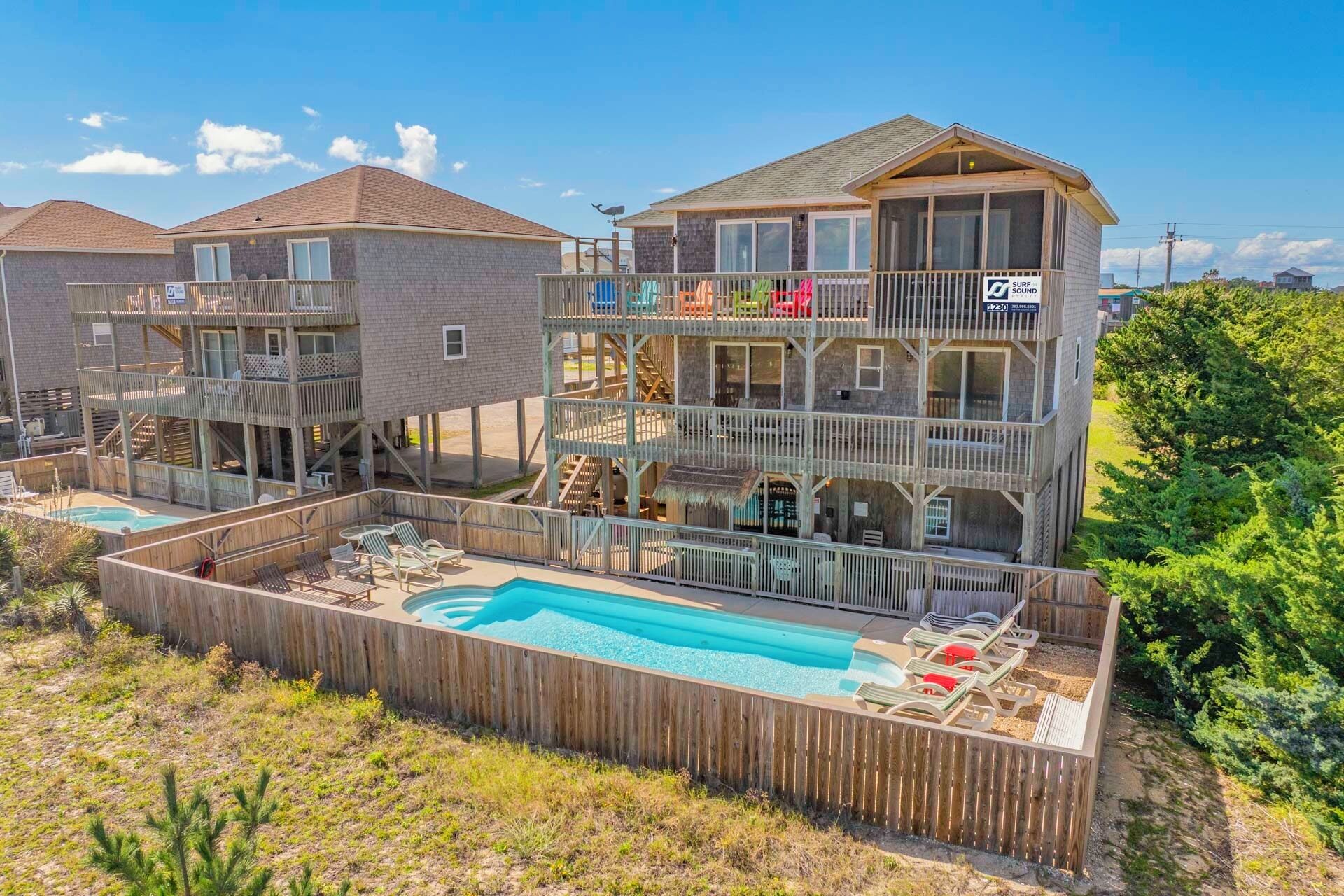 A multi-story building with a swimming pool, outdoor seating, and a deck area.
