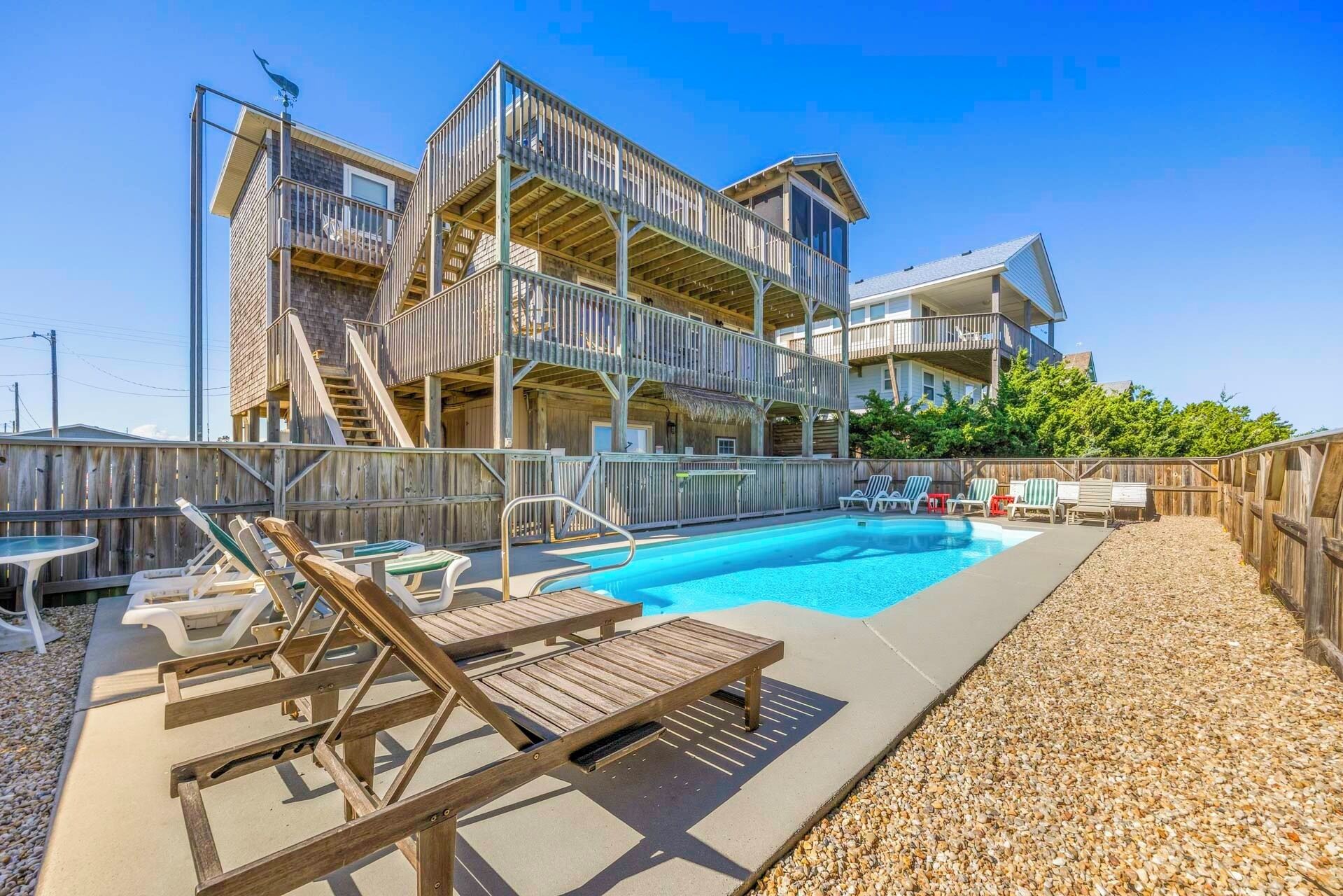 A multi-level building with a pool area, including lounge chairs and a staircase.