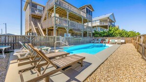 Ein mehrgeschossiges Gebäude mit Poolbereich, einschließlich Liegestühlen und einer Treppe.
