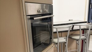 Uma cozinha com forno embutido, uma mesa de jantar e dois bancos altos.