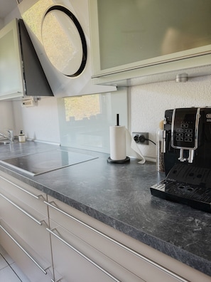 Een moderne keuken met een ingebouwde espressomachine, een keukenrolhouder en een roestvrijstalen spoelbak.