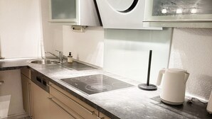 Uma cozinha moderna com uma pia dupla, fogão embutido e chaleira sobre a bancada.