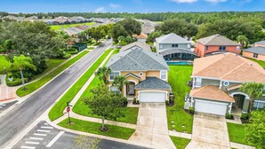 A suburban neighborhood with single-family homes, a stop sign, and a clear road. - Adventure Awaits Manor (Kissimmee)