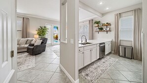 A modern living room with a grey sofa, a black leather chair, and a large window with blinds. - Magical Lake View Escape! (Kissimmee)