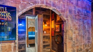 A room with a brick wall, a bed with a headboard, and a wooden door.