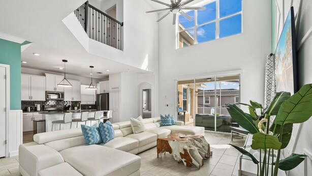 A spacious living area with a large sectional sofa, a coffee table, and a ceiling fan.