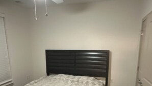 Un dormitorio con cama, ventilador de techo y armario.