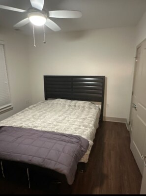 Een slaapkamer met een bed, een plafondventilator en een kledingkast.