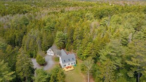 Ilmakuva talosta, jonka ympärillä on tiheä metsä.