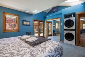Camera da letto con un letto, un'ampia finestra, una lavatrice e una porta che dà su un balcone.