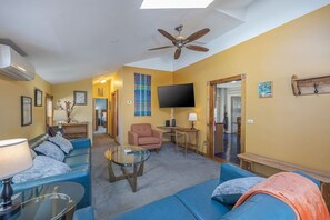 A living room with a ceiling fan, a flat-screen TV, a sofa, a coffee table, and a fireplace. - 3BR Apt Center of Bar Harbor! [Blueberry Bungalow] (Bar Harbor)