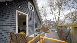 A deck with wicker furniture, a table, and a bench. - Renovated 3BR Home in Downtown SWH [Mariners Rest] (Southwest Harbor)
