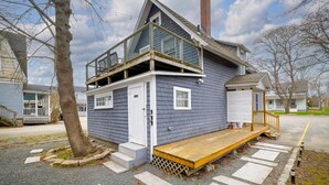 A two-story house with a balcony, a front porch, and a driveway. - Renovated 3BR Home in Downtown SWH [Mariners Rest] (Southwest Harbor)