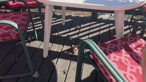 Une terrasse en bois avec une table ronde et des chaises, donnant sur un lac et une forêt.
