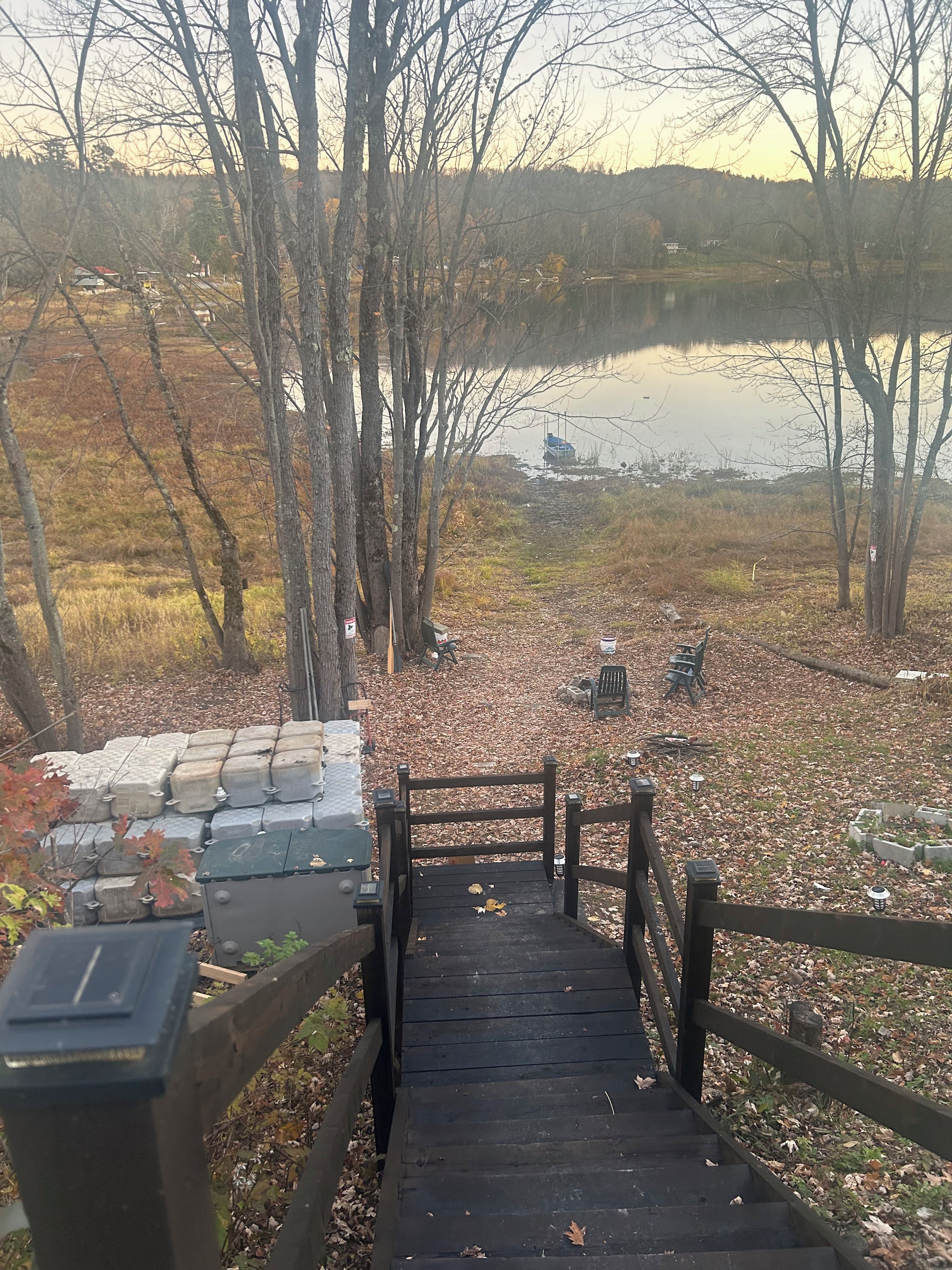 A wooden staircase leading to a dock over a calm lake, surrounded by trees and a grassy area.