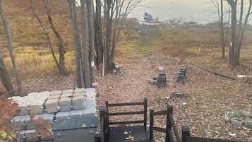 A wooden staircase leading to a dock over a calm lake, surrounded by trees and a grassy area.