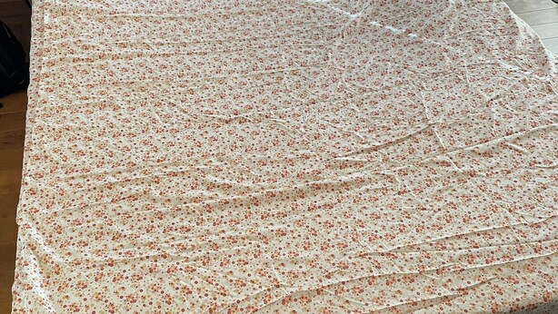 Una cama con colcha estampada, suelo de madera y un sillón con diseño.