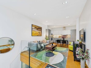 Un apartamento moderno con barandilla de vidrio, comedor y cocina.