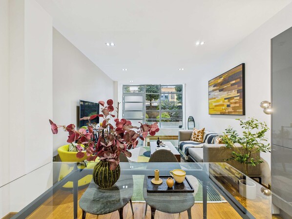 A modern living room with a glass coffee table, a sofa, and a TV.