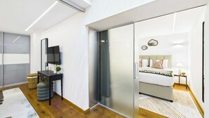 Ein modernes Schlafzimmer mit einem Bett, Nachttischen, einem Fernseher und einer Schiebetür zu einem weiteren Raum.