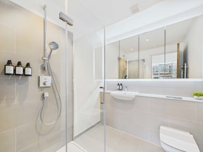 Une salle de bain moderne avec une douche à parois de verre, des toilettes et un lavabo avec un miroir au-dessus.