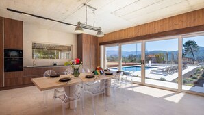 Eine moderne Küche mit Holzausstattung, einem Einbauofen und einem großen Fenster mit Blick auf einen Pool und Berge.