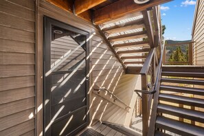 A wooden exterior with a sliding glass door, a metal staircase, and a view of the surrounding landscape. - Big Sky Resort Studio | Walk to the Shuttle (Big Sky)