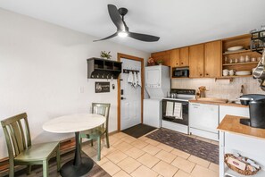 A compact kitchen with a dining area, a ceiling fan, wooden cabinets, a microwave, a dishwasher, and a small table with chairs.