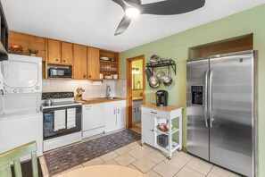 A compact kitchen with white appliances, wooden cabinets, and a green accent wall.