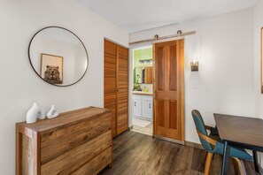 A room with a wooden dresser, a round mirror, and a dining table with chairs. - Big Sky Resort Studio | Walk to the Shuttle (Big Sky)