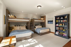 Une chambre avec des lits superposés, une bibliothèque et un tableau accroché au mur.