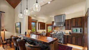 A spacious kitchen with a large island, wooden cabinets, stainless steel appliances, and pendant lighting. - Ski-In/Ski-Out Luxury | Cowboy Heaven Retreat (Big Sky)