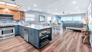 Een moderne keuken met een groot eiland, inbouwapparatuur en een eetgedeelte met uitzicht.