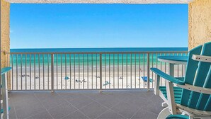 Een balkon met uitzicht op het strand, met een leuning en enkele stoelen.