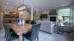 Ein modernes Wohnzimmer mit einem Holzesstisch, schwarzen Stühlen, einem grauen Sofa und einer Treppe zu einer oberen Ebene.