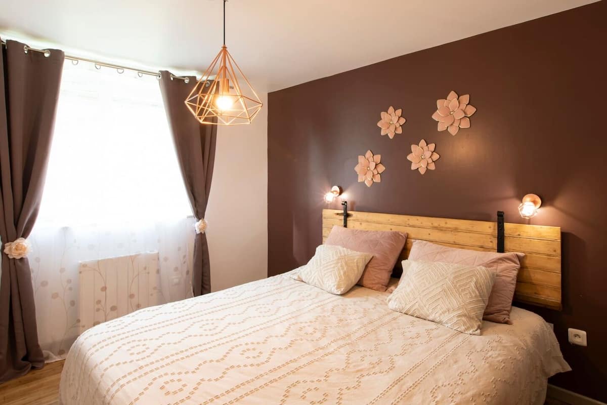 A bedroom with a wooden headboard, a patterned bedspread, and decorative wall sconces.